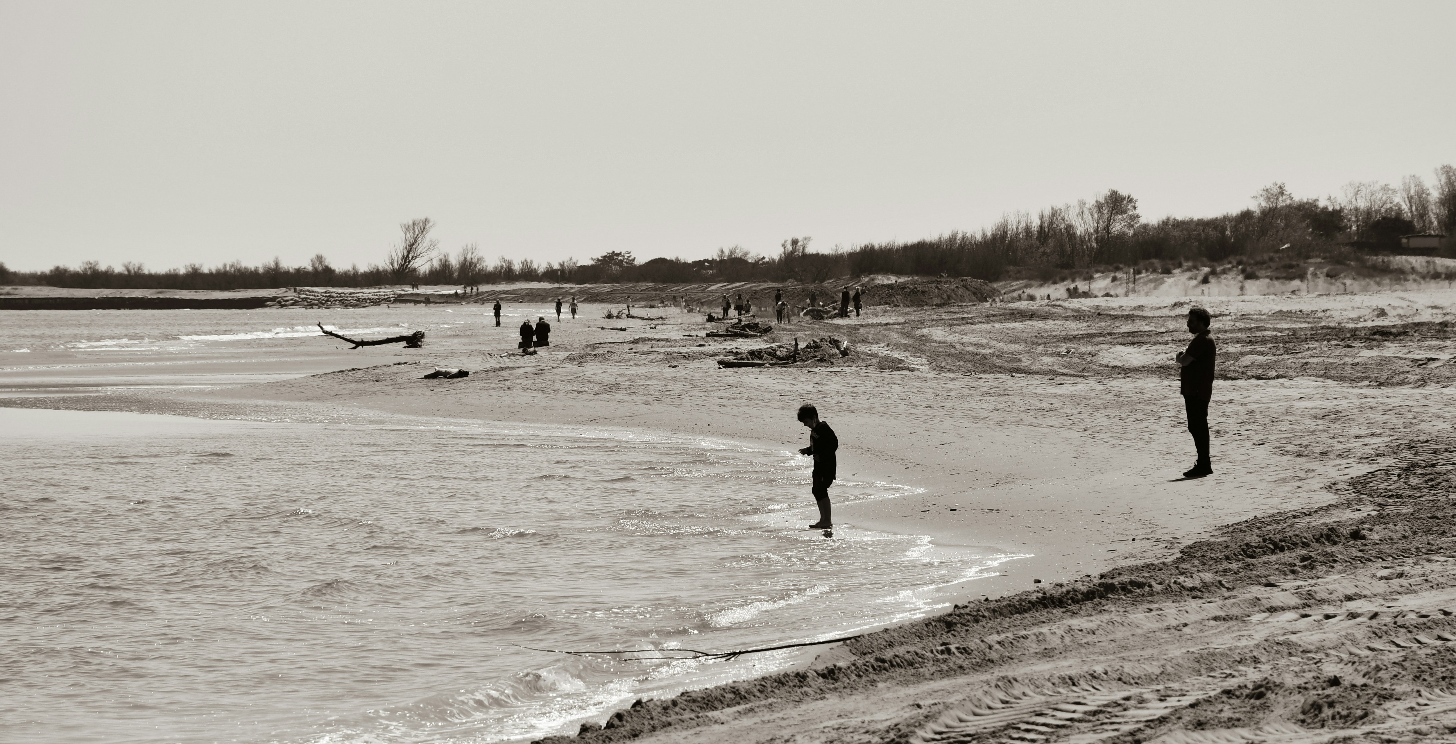 man in black jacket walking on white sand beach during daytime